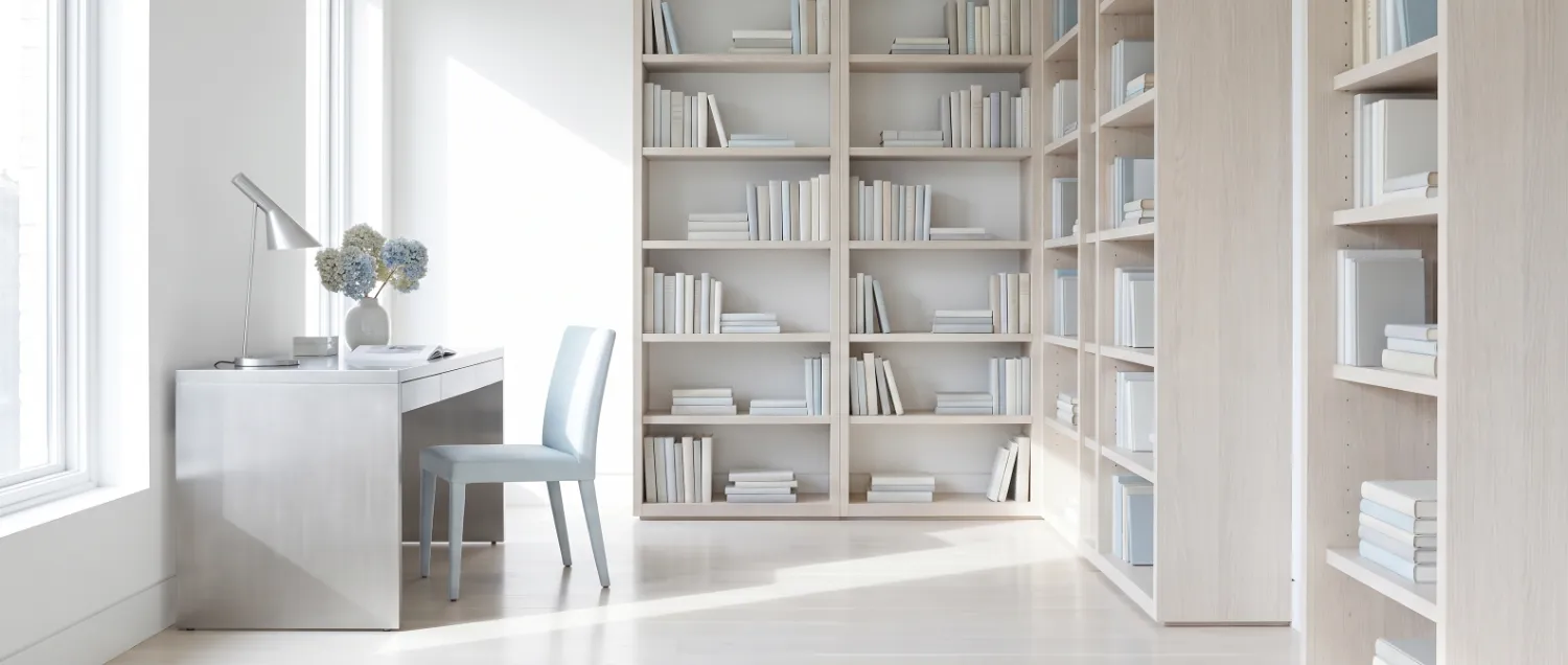 Corner of a bright reading room with tall shelves and a plain desk