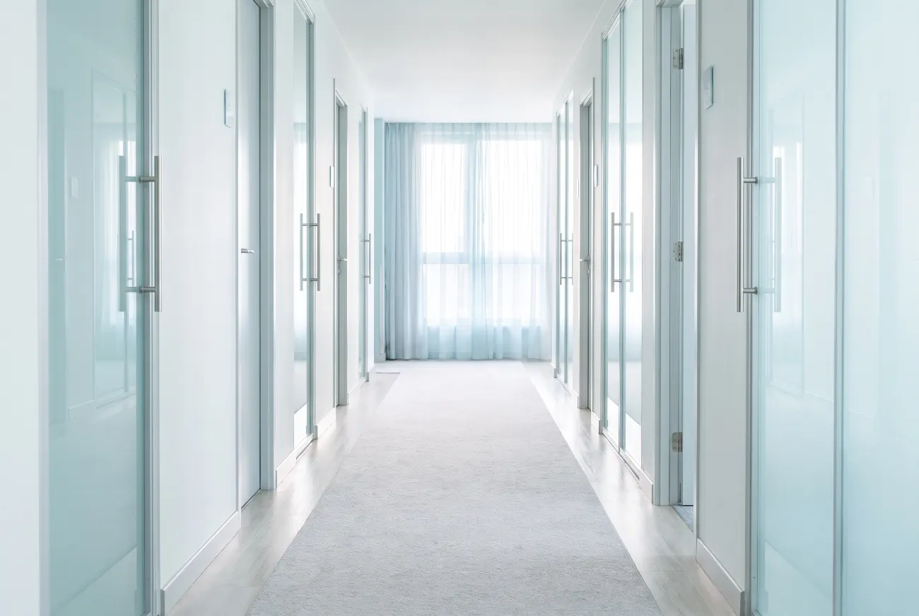 Bright hotel corridor with pale doors receding