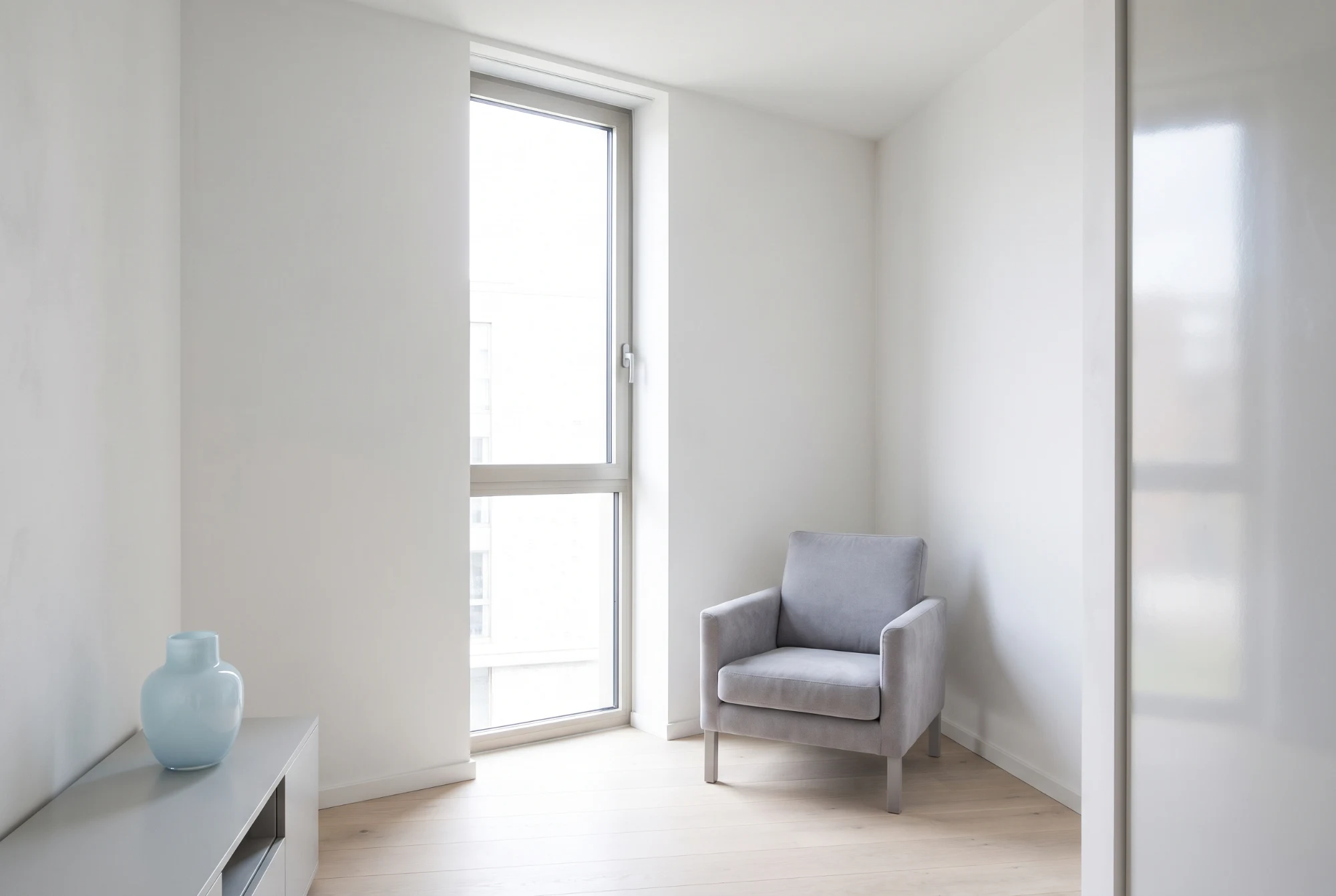 Quiet corner of a bright room with daylight across pale oak boards