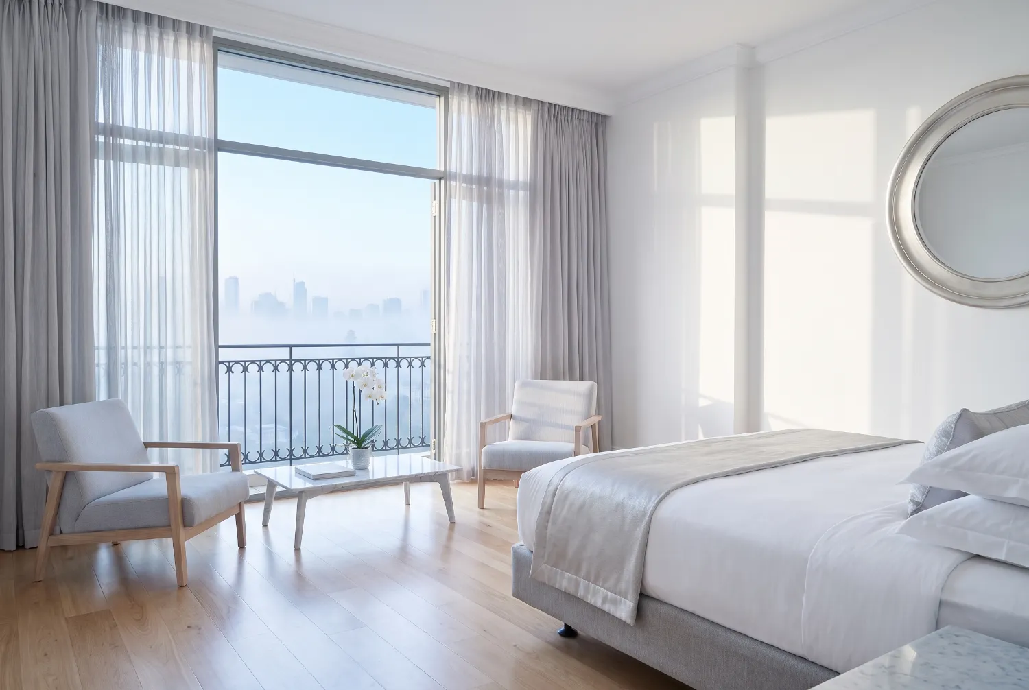 Empty hotel room in morning light with a linen curtain drawn from a tall window