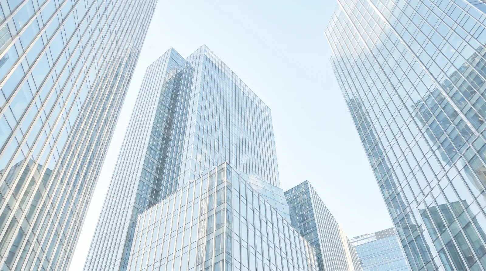 Glass office towers in a financial district under a clear pale sky