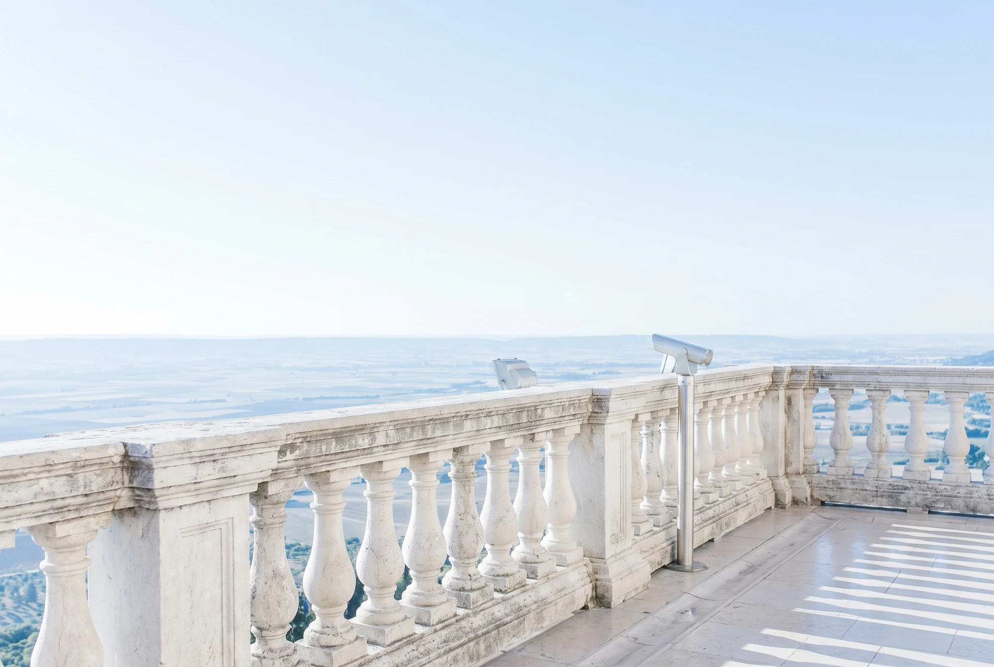 Stone balustrade overlooking an open valley in clear morning light