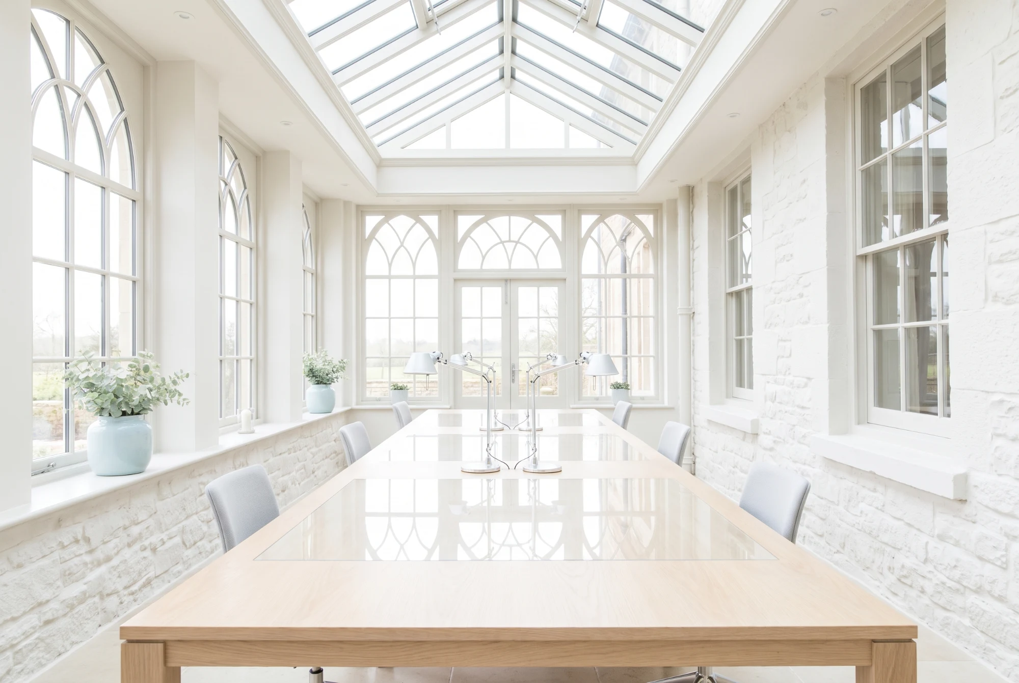 Orangery used as a working space, long table under a glazed roof