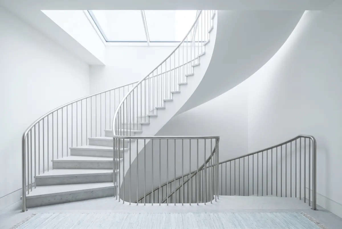 Pale stone spiral staircase lit from a rooflight above